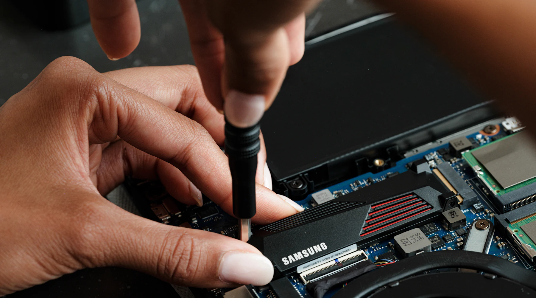 Reparatie van een laptop: een SSD wordt met een schroevendraaier vastgezet