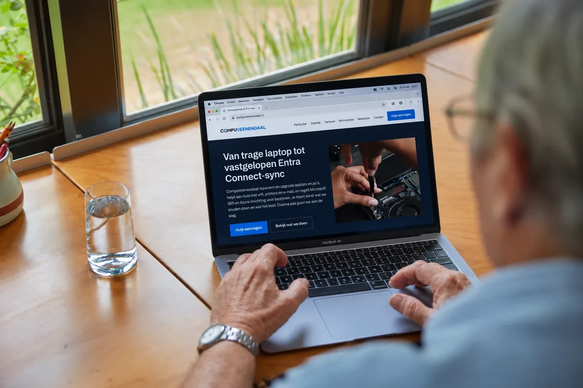 Iemand bekijkt thuis aan de eettafel de website van CompuVeenendaal op een laptop