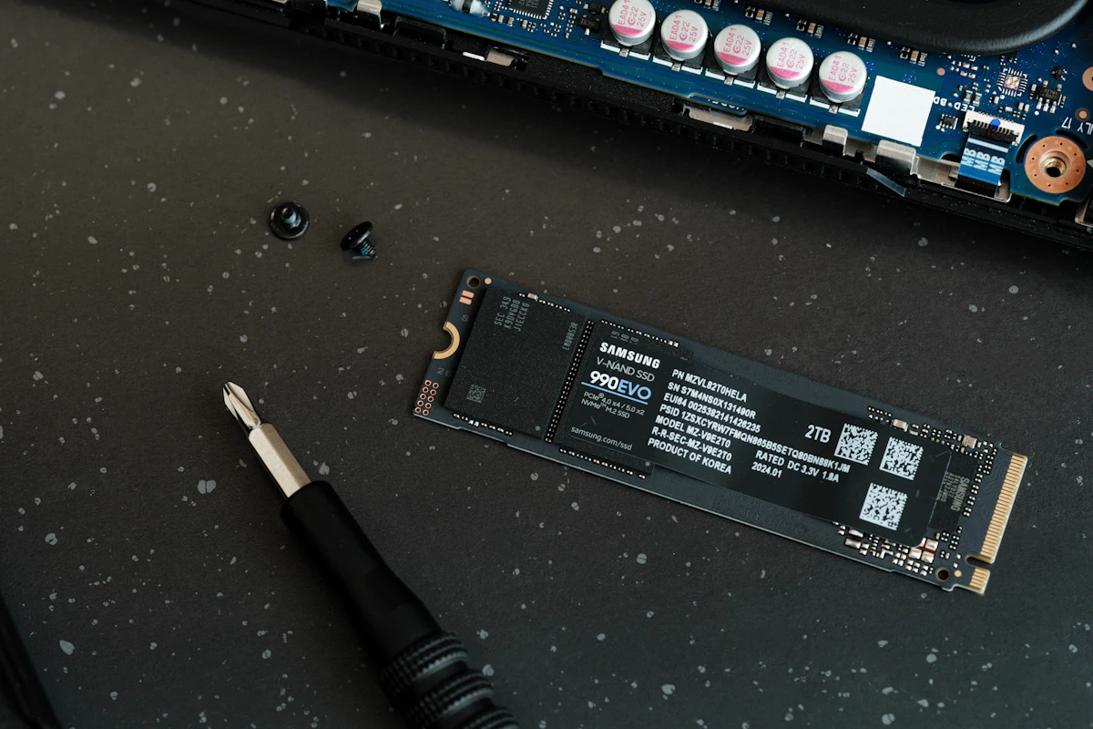 Losse SSD en schroevendraaier naast een geopende laptop